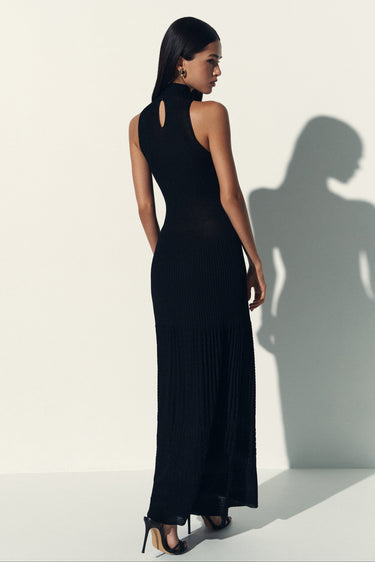 Woman wearing a black sleeveless dress with a plain background