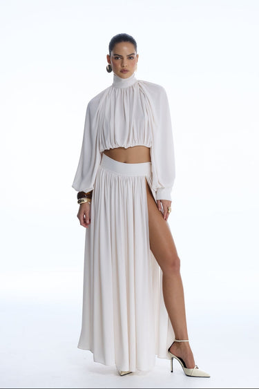 Woman wearing a white outfit with a high slit on a white background