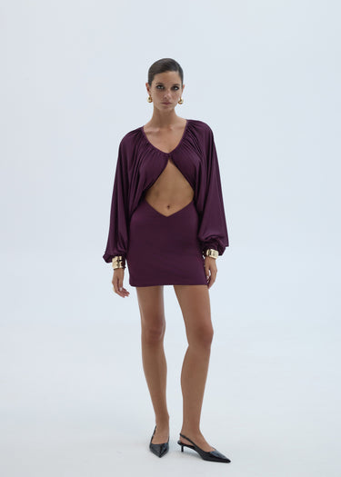 Woman wearing a burgundy dress with a cutout design on a white background