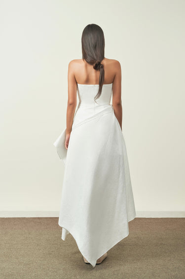 Woman wearing a strapless white dress with a plain background