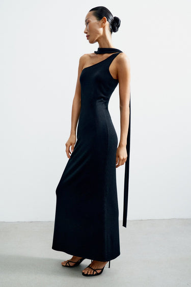 Woman wearing a black one-shoulder dress with a long ribbon on a white background