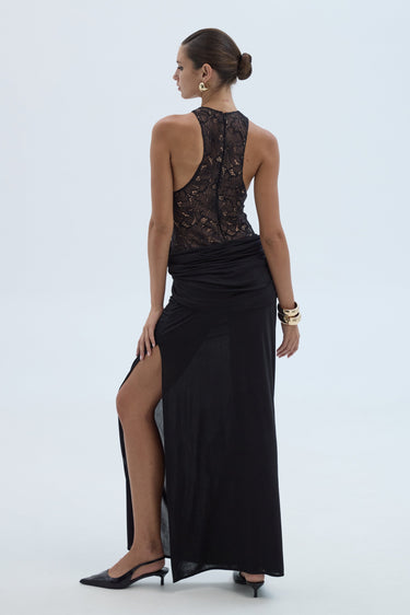 Woman wearing a black evening gown with a high slit on a white background