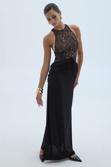 Woman wearing a black evening gown with lace detailing on a white background