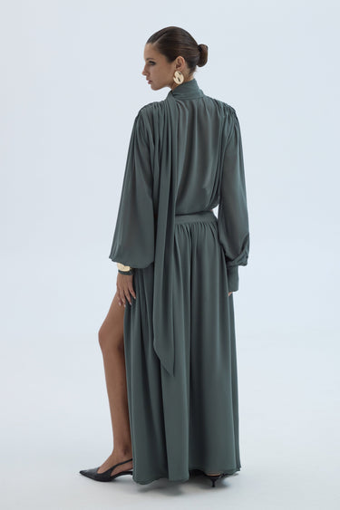 Woman wearing a long green dress with a high collar on a white background