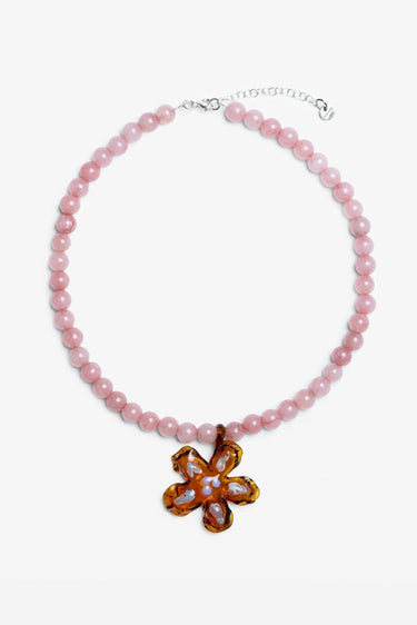 Pink beaded necklace with a floral pendant on a white background