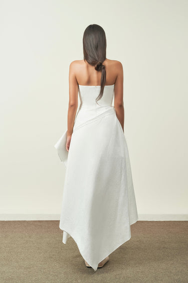Woman wearing a strapless white dress with a plain background
