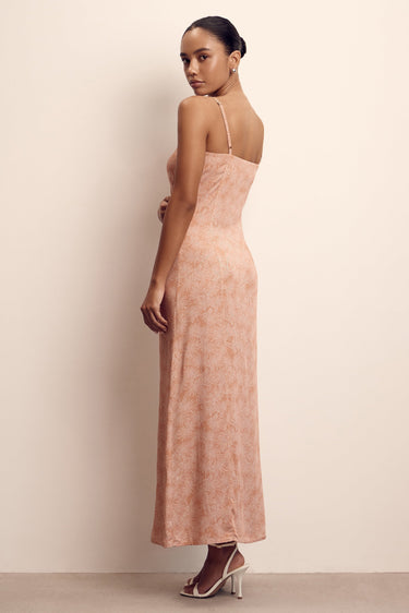 Woman wearing a long, light pink dress against a beige background